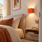 Applique murale orange sans fil à côté d'un lit